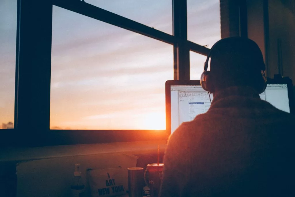 a man wearing headphones checking his email during a sunset